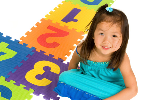 Chinese little girl seated beside colorful hopscotch game