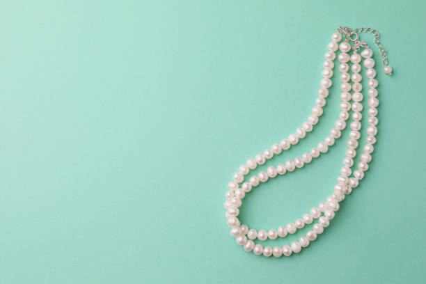 istock Elegant pearl necklace on turquoise background, top view. Space for text 1747049912