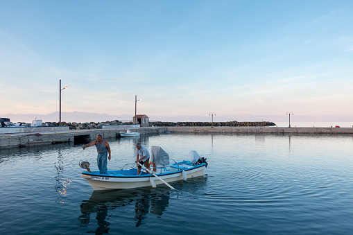 September 14th 2022 - Mathraki, Greece - Two fishermen docking their boat in Mathraki island, Greece