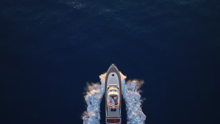 AERIAL Above a yacht at sea as the sun is setting