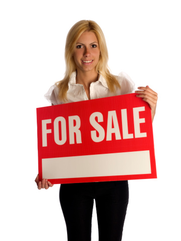 Cheerful businesswoman holding for sale sign