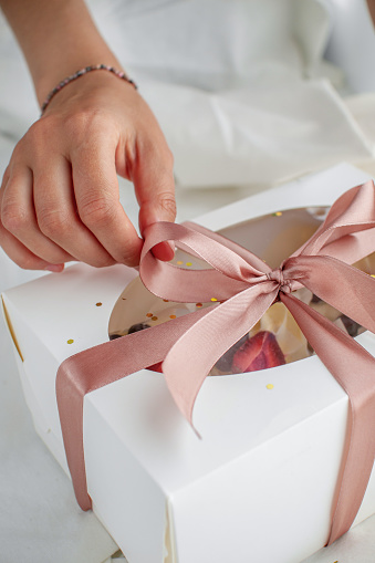 A young woman on a pastry chef wrapping a sweet holiday gift. Delivery of gifts