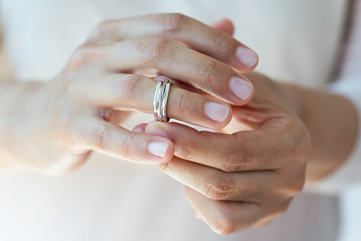 Hands of caucasian female who is about to taking off her wedding ring.