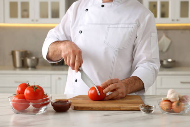istock Professional chef cutting tomatoes at white marble table indoors, closeup 1747093804