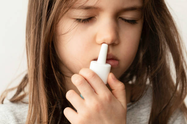 menina usando spray de nariz - child human nose allergy spraying - fotografias e filmes do acervo