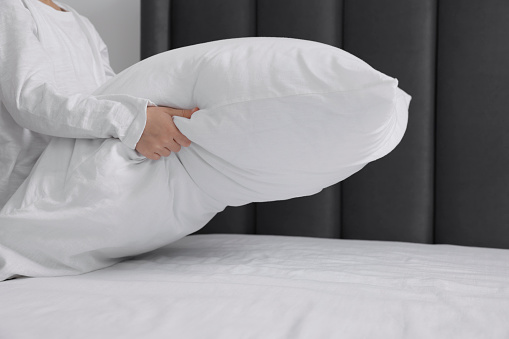 Girl changing bed linens in bedroom, closeup