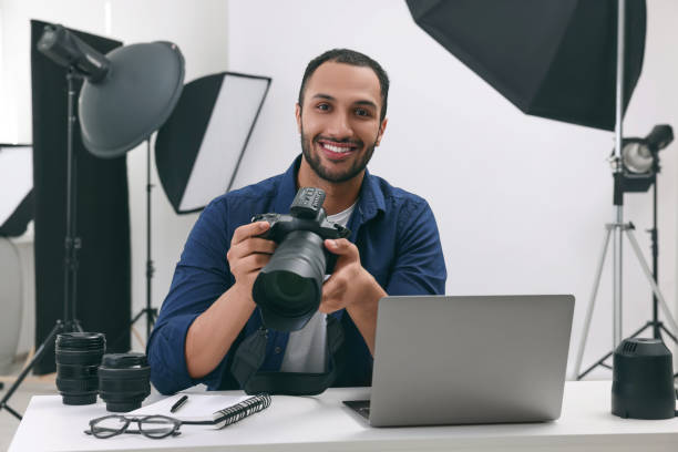 現代の写真スタジオのテーブルにカメラを持つ若いプロの写真家 - office tool flash ストックフォトと画像