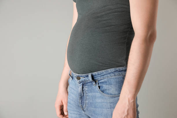 istock Overweight man in tight tshirt and jeans on light grey background, closeup. Space for text 1747113670