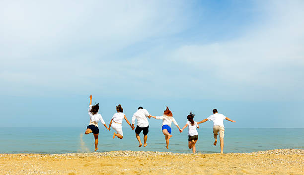 people holding hands and running to sea side,