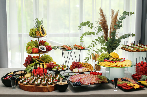 catering buffet table with snacks and appetizers. Set of varios fruits and berries. Decorative vase. Wedding event