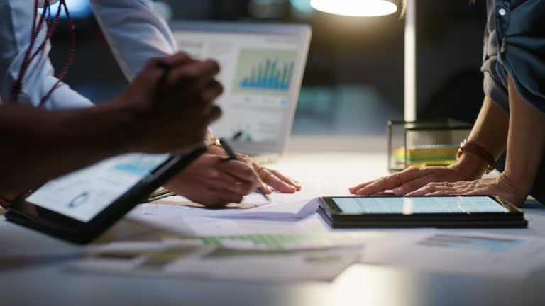 Business people, hands and planning at night in teamwork, project deadline or strategy at office. Group or employees working late in brainstorming, analytics or statistics in marketing at workplace