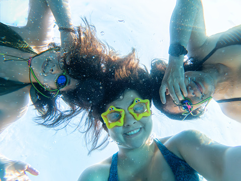 Family of Chinese and multiracial women posing for underwater selfie in an outdoor pool.  George Town, Penang, Malaysia.