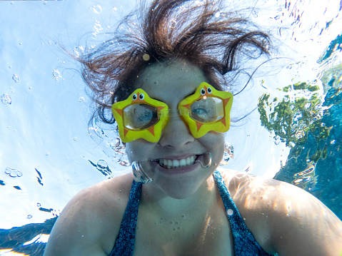 Eurasian young woman posing for underwater selfie in an outdoor pool.  George Town, Penang, Malaysia.