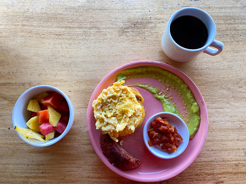 View of a Colombian breakfast with fruits, eggs, coffee and arepa.