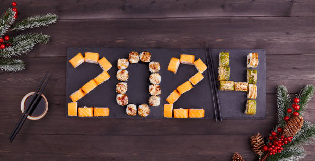 2024년 새해 복 많이 받으세요 인사 배너. 참치, 연어, 장어, 아보카도, 야채를 곁들인 다양한 스시 롤 세트. - hosomaki 뉴스 사진 이미지