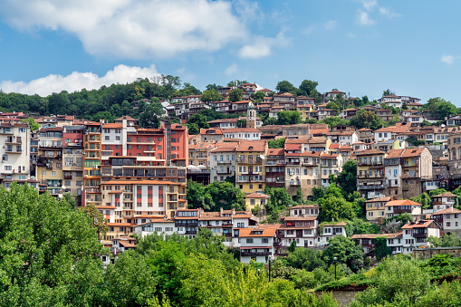 Veliko Tarnovo: a historic city in Bulgaria, with its terraced houses, medieval architecture, and the imposing Tsarevets Fortress perched on a hill, overlooking the meandering Yantra River.