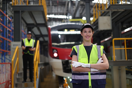 Portrait of a female electrical engineer arm crossing in front of the electrical train at the Train station