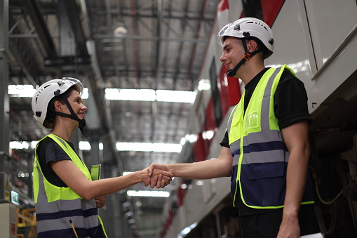 A couple of Rail engineers shook hands in a Train Station after completing the job.