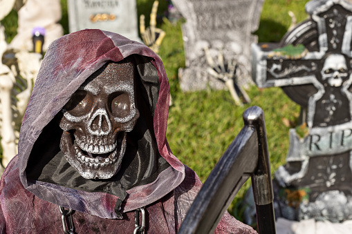 Grim Reaper holds scythe in Halloween decorated yard