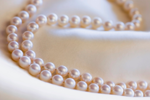 A lovely strand of natural Mikimoto pearls casually draped over creamy silk fabric of the same color.SEE similar: