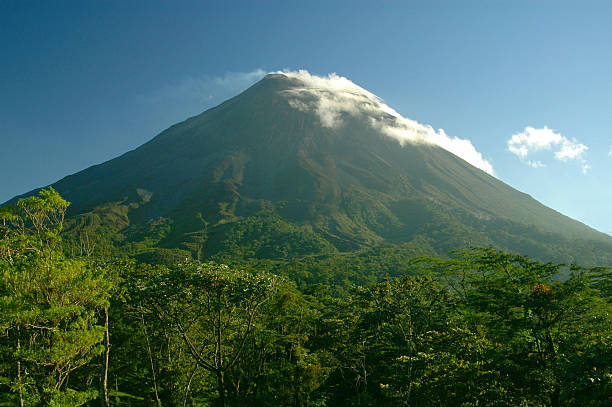 Vulcão Arenal Costa Rica. Nuvem casquinha coberta contra o céu azul. - foto de acervo