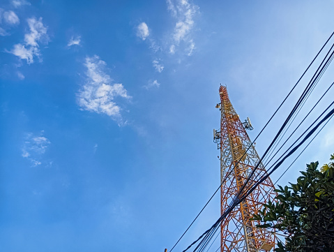 Behold the towering communication structure reaching for the clear blue sky, a symbol of connectivity and progress.
