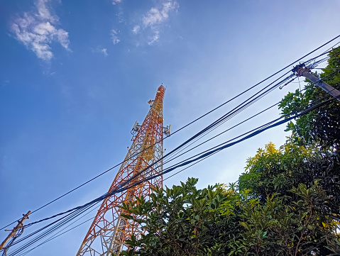 Capture the essence of connectivity as the communication tower stands tall against the azure skies, linking the world under a brilliant sun.