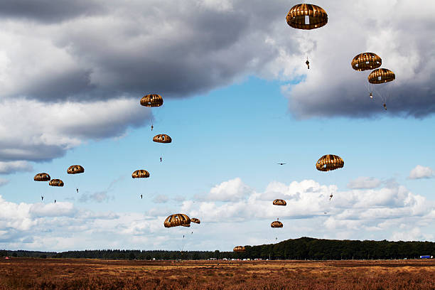 Military parachutist paratroopers parachute jumping out of a air force planes on a clear blue sky day.