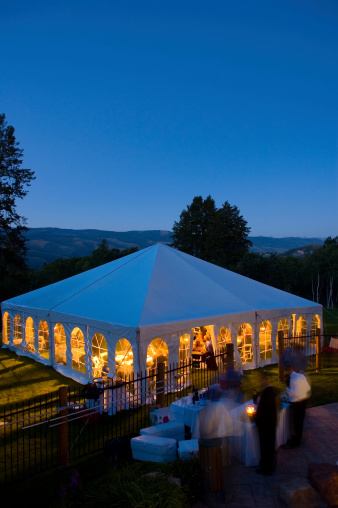 Entertainment Tent at Dusk Glowing with Warm Light.  Wedding and corporate event party with bartender and copy space.
