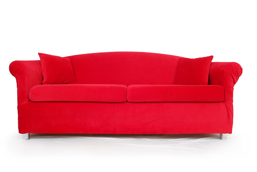 Horizontal image of a big red couch with silver legs sitting on a white background. The fabric is a bright and vibrant red velvet-like material. The bright color contrasts nicely on the white background.