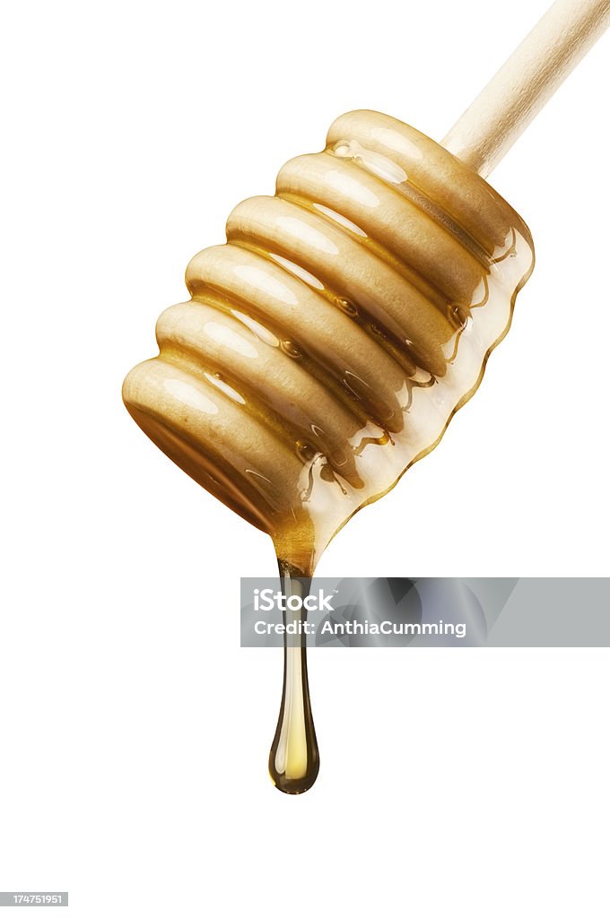 Pure golden manuka honey pouring from a wooden drizzler Pure golden honey pouring over a wooden serving drizzler Manuka honey Stock Photo