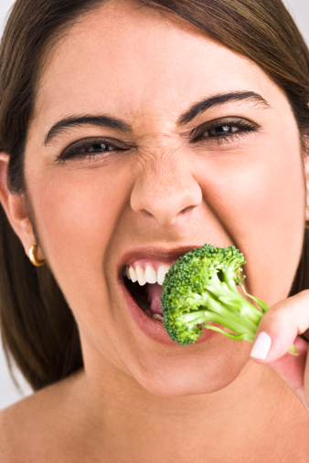 Portrait of woman eating a broccoli