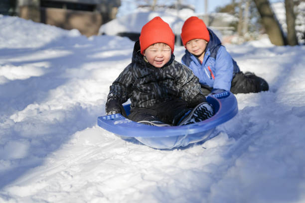 istock Little Boys Sliding in the Snow Outdoors in Winter 1747520717