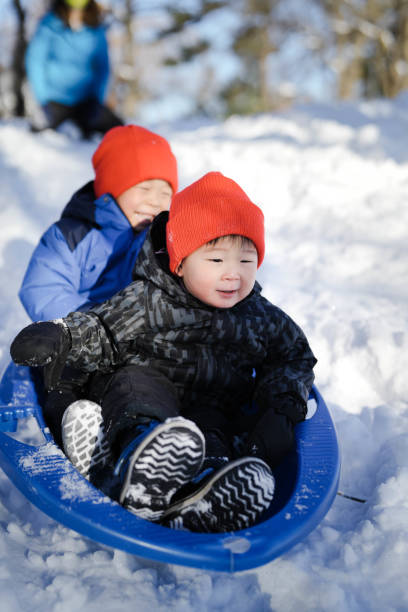 istock Mother and Sons Sliding in the Snow Outdoors in Winter 1747520719