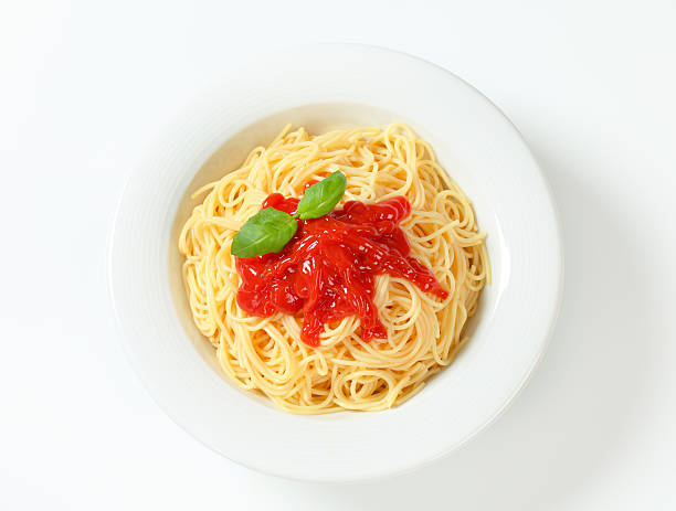 plate of freshly boiled spaghetti with a tomato sauce and basil leaves