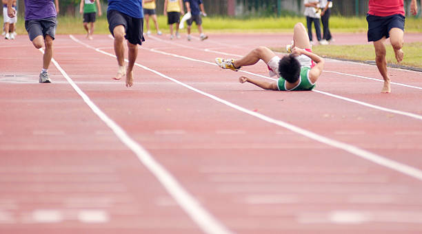 Fallen Sprinter A sprinter falling on the race track. athlete fails stock pictures, royalty-free photos & images