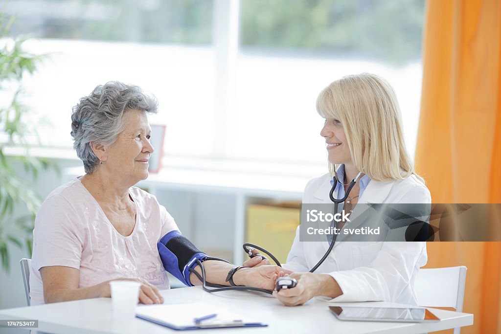 Senior woman at doctor's office. Mature female doctor measuring senior woman's blood pressure.See more LIFESTYLE and MEDICAL images with this WOMEN. Click on image below for lightbox. Doctor Stock Photo