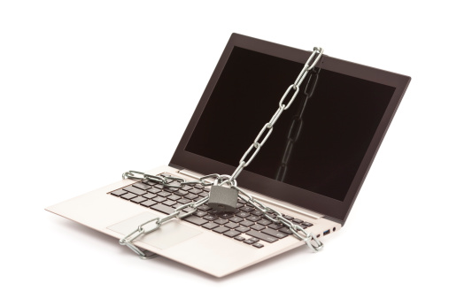 Chain with a padlock around open laptop, isolated over white background, cut out image.