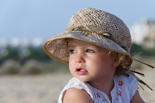 Close-up of the face of a small girl with a hat in the head