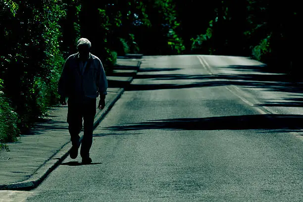 Photo of Solitude Old Man Walking Alone On An Empty Road