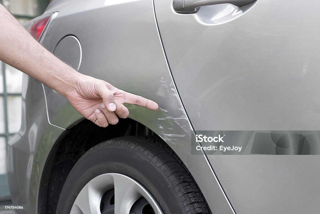 Car Accident Damage Close-up of hand pointing to scrape mark on gray car. Car Stock Photo