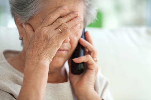 Crying senior woman sitting on sofa and talking on the phone. Hand on her face.See more LIFESTYLE and MEDICAL images with this WOMEN. Click on image below for lightbox.