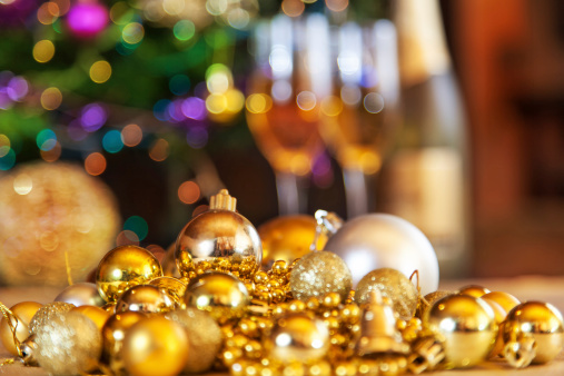 Christmas decoration with golden beads and ornaments. Two glasses and the bottle of champagne are in the backround.
