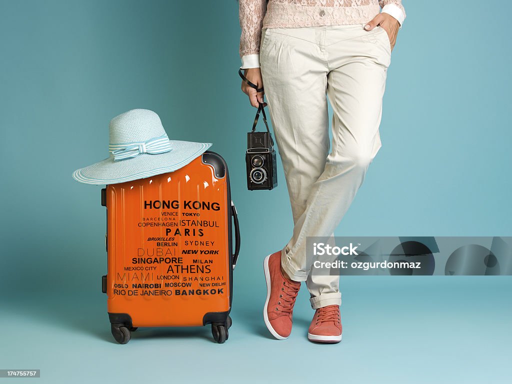 Donna in piedi con una valigetta accanto a lei - Foto stock royalty-free di Viaggio
