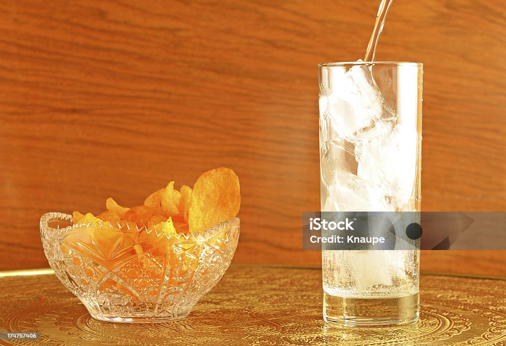 Vaso de agua helada y papas fritas sobre mesa de latón - Foto de stock de Agua libre de derechos