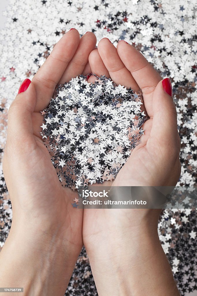 Wishing on a star Hands holding pile of decorative silver stars Confetti Stock Photo