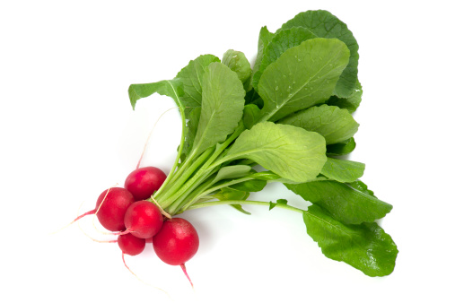 Fresh red radishes in a white colander. Farm organic vegetables. Gray background. Top view