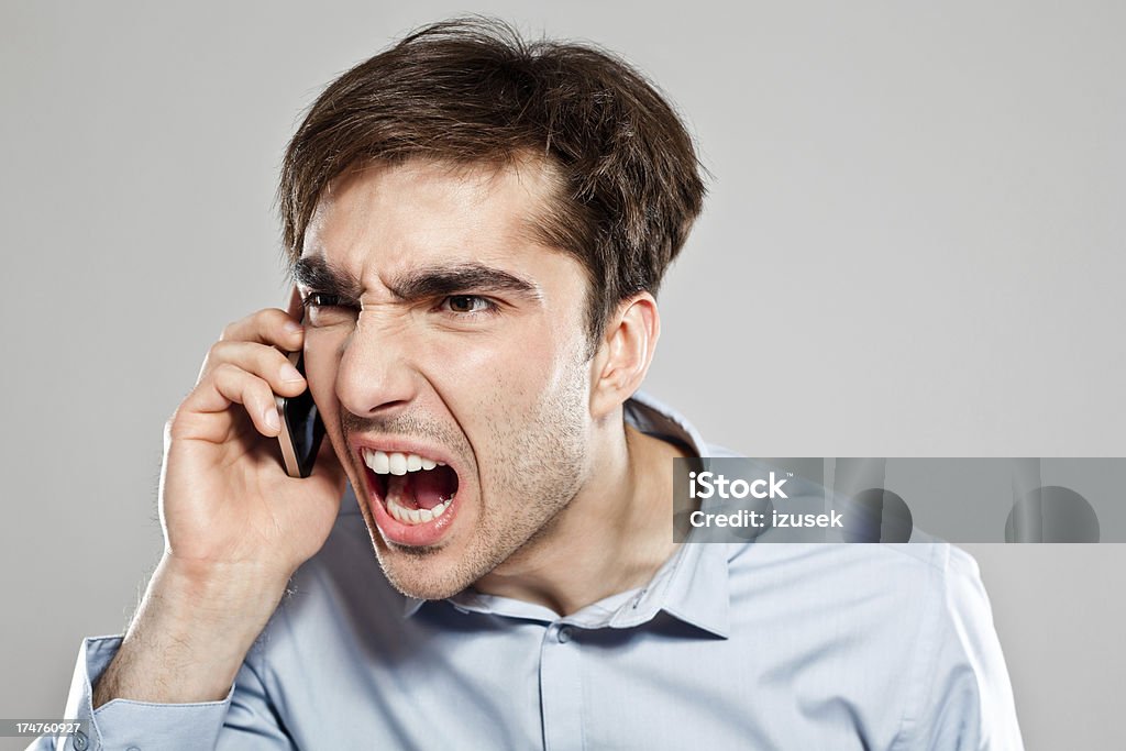 Frustration Portrait of young businessman screaming into the mobile phone. 25-29 Years Stock Photo