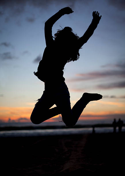 シルエットは、女の子をジャンプ夕暮れのビーチ - arms outstretched teenage girls jumping flying ストックフォトと画像