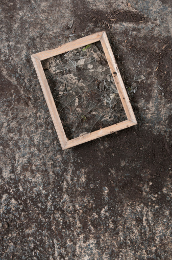 An empty broken picture frame is left behind on the concrete after a flood.